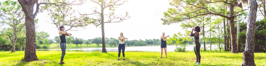 Women stretching lakeside on the grass among trees